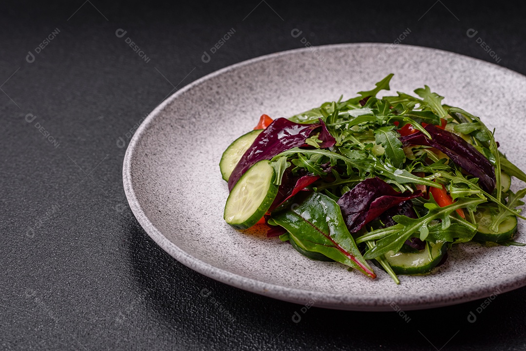 Deliciosa salada suculenta com salmão, tomate, pepino, ervas, sementes de abóbora, sal e especiarias em uma placa cerâmica sobre um fundo escuro de concreto