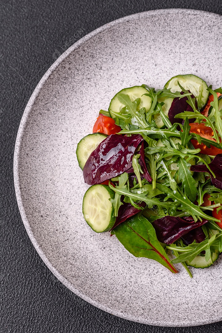 Deliciosa salada suculenta com salmão, tomate, pepino, ervas, sementes de abóbora, sal e especiarias em uma placa cerâmica sobre um fundo escuro de concreto