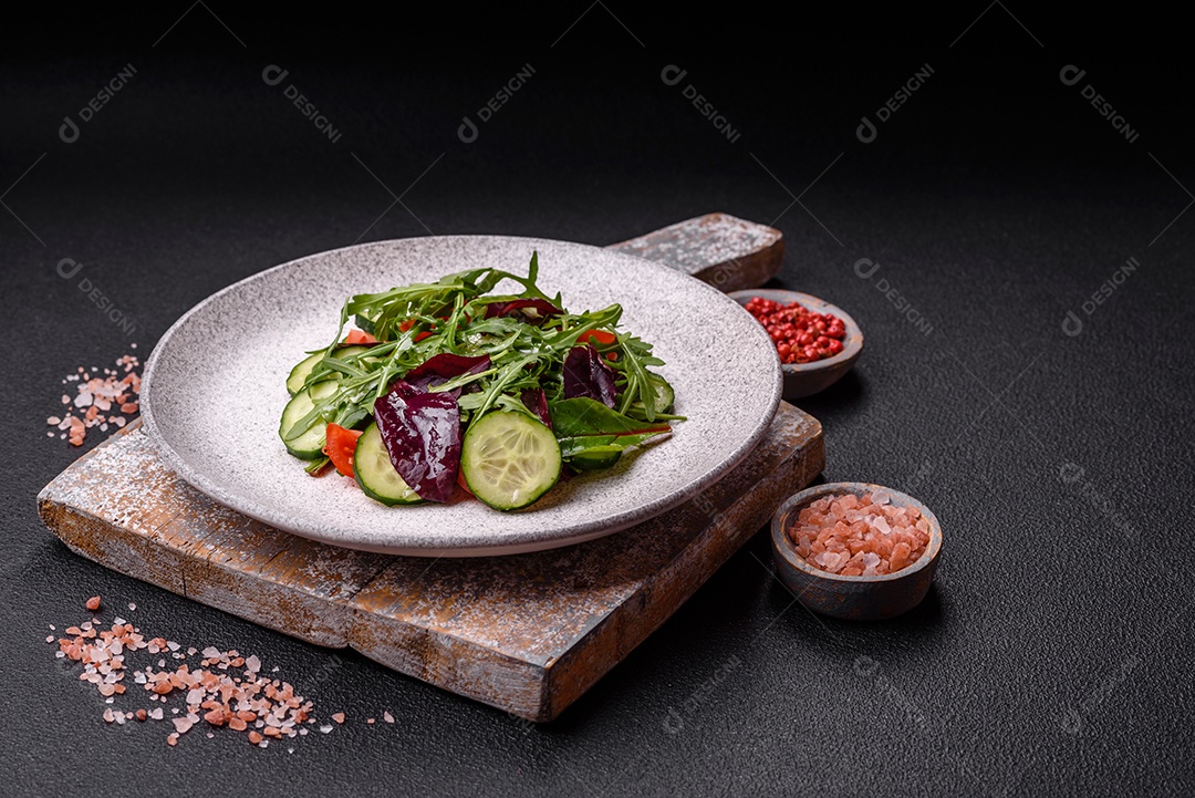 Deliciosa salada suculenta com salmão, tomate, pepino, ervas, sementes de abóbora, sal e especiarias em uma placa cerâmica sobre um fundo escuro de concreto