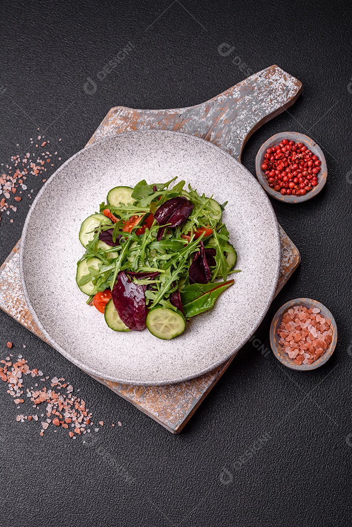 Deliciosa salada suculenta com salmão, tomate, pepino, ervas, sementes de abóbora, sal e especiarias em uma placa cerâmica sobre um fundo escuro de concreto