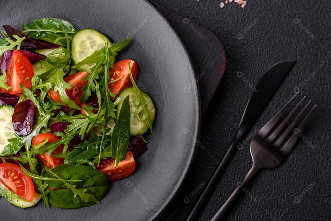 Deliciosa salada suculenta com salmão, tomate, pepino, ervas, sementes de abóbora, sal e especiarias em uma placa cerâmica sobre um fundo escuro de concreto