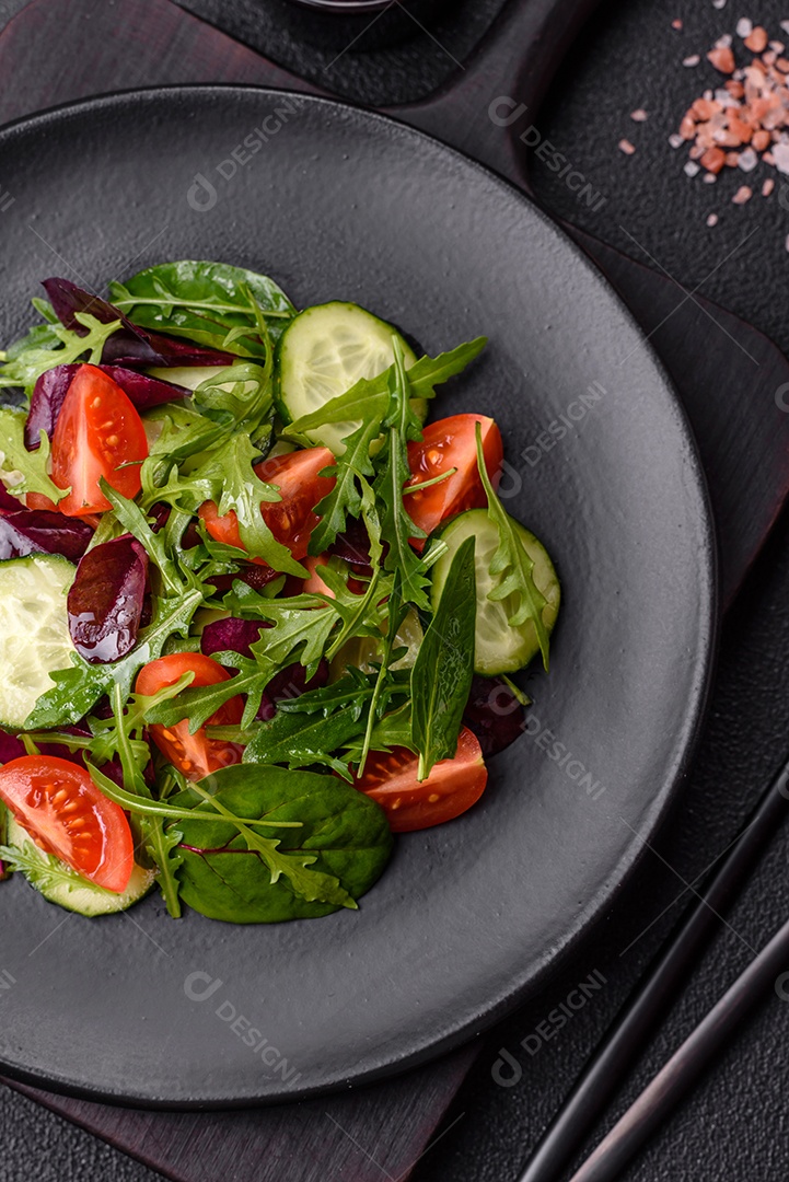 Deliciosa salada suculenta com salmão, tomate, pepino, ervas, sementes de abóbora, sal e especiarias em uma placa cerâmica sobre um fundo escuro de concreto
