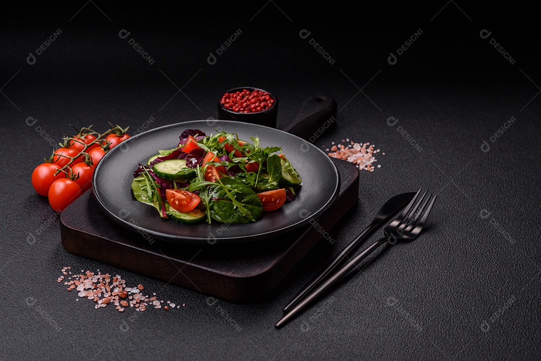 Deliciosa salada suculenta com salmão, tomate, pepino, ervas, sementes de abóbora, sal e especiarias em uma placa cerâmica sobre um fundo escuro de concreto