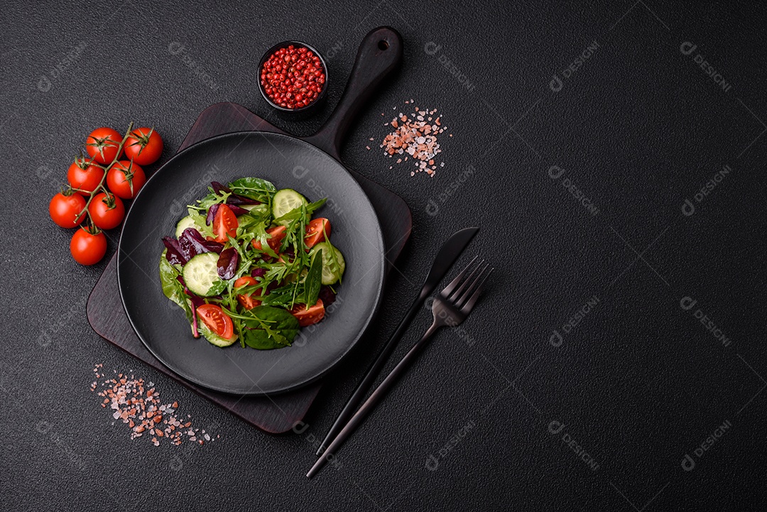 Deliciosa salada suculenta com salmão, tomate, pepino, ervas, sementes de abóbora, sal e especiarias em uma placa cerâmica sobre um fundo escuro de concreto