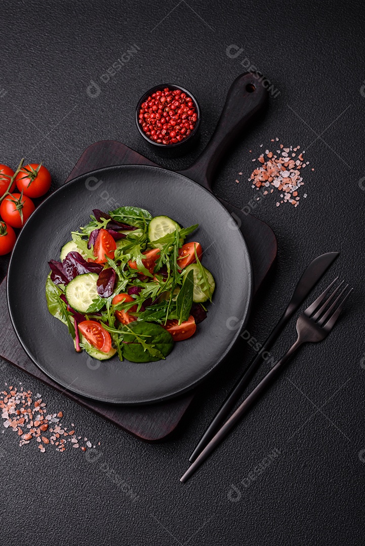 Deliciosa salada suculenta com salmão, tomate, pepino, ervas, sementes de abóbora, sal e especiarias em uma placa cerâmica sobre um fundo escuro de concreto
