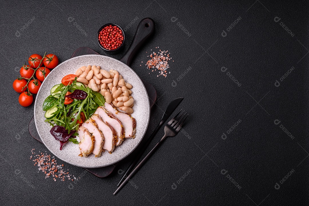Deliciosa salada suculenta com salmão, tomate, pepino, ervas, sementes de abóbora, sal e especiarias em uma placa cerâmica sobre um fundo escuro de concreto