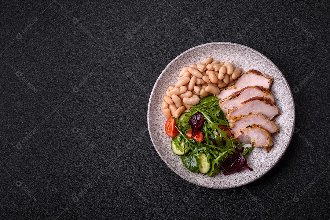 Deliciosa salada suculenta com salmão, tomate, pepino, ervas, sementes de abóbora, sal e especiarias em uma placa cerâmica sobre um fundo escuro de concreto