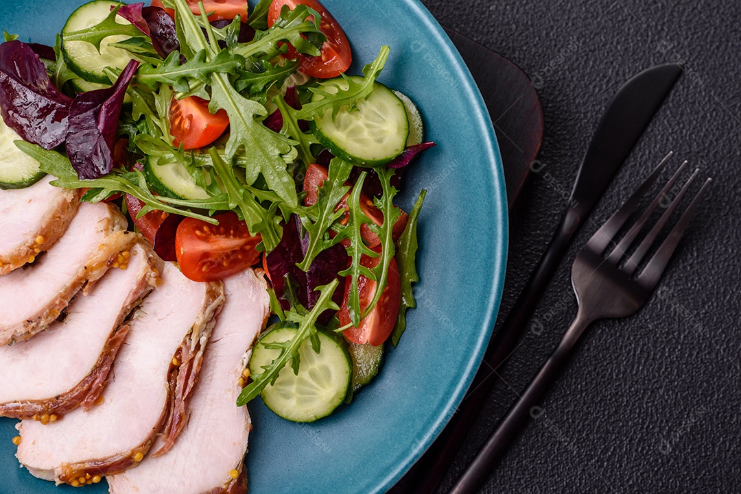 Deliciosa salada suculenta com salmão, tomate, pepino, ervas, sementes de abóbora, sal e especiarias em uma placa cerâmica sobre um fundo escuro de concreto