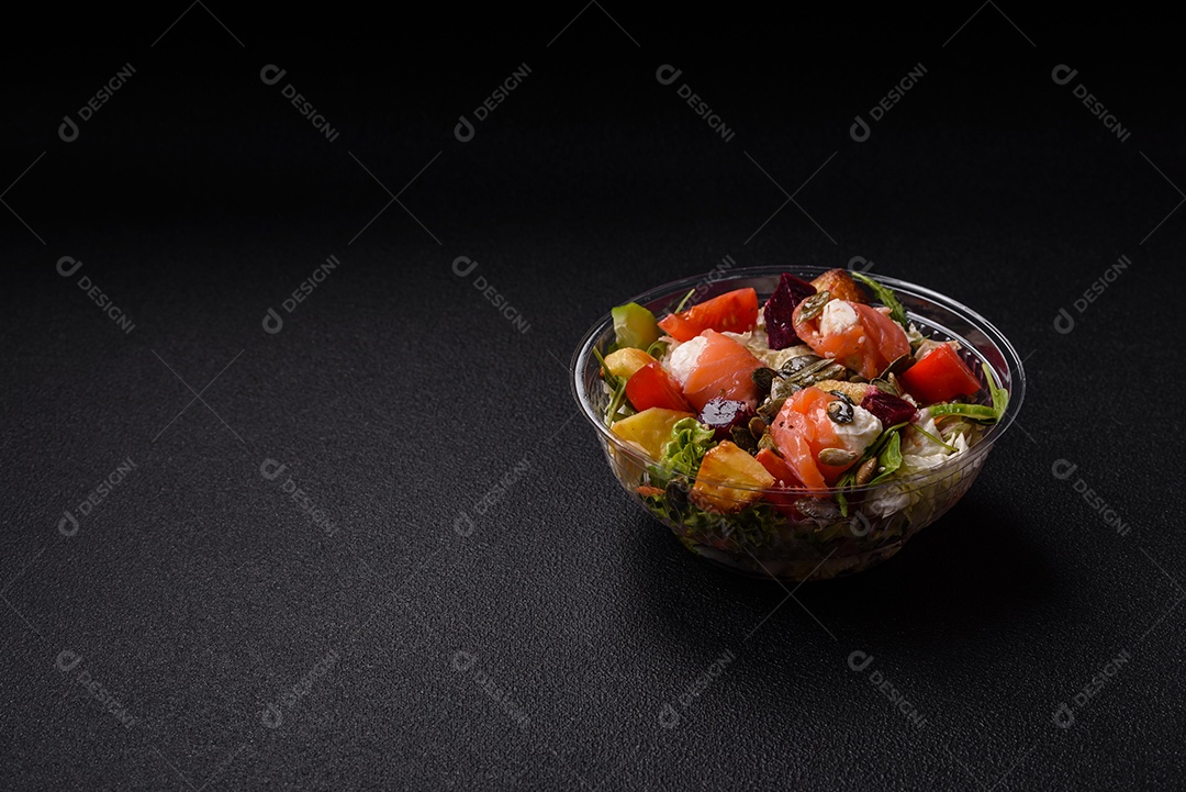 Deliciosa salada suculenta com salmão, tomate, pepino, ervas, sementes de abóbora, sal e especiarias em uma placa cerâmica sobre um fundo escuro de concreto