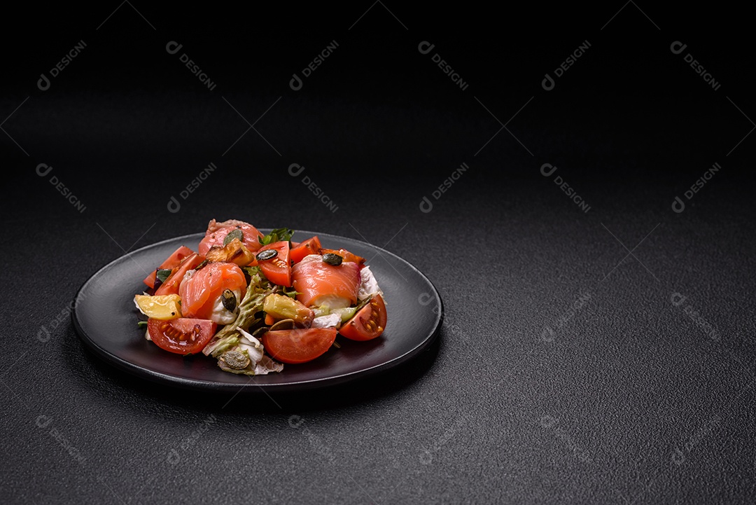 Deliciosa salada suculenta com salmão, tomate, pepino, ervas, sementes de abóbora, sal e especiarias em uma placa cerâmica sobre um fundo escuro de concreto