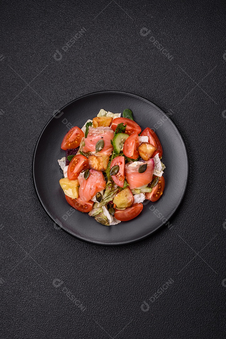 Deliciosa salada suculenta com salmão, tomate, pepino, ervas, sementes de abóbora, sal e especiarias em uma placa cerâmica sobre um fundo escuro de concreto