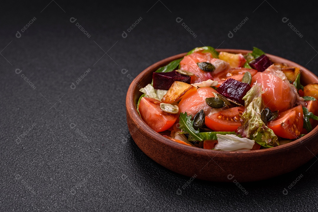 Deliciosa salada suculenta com salmão, tomate, pepino, ervas, sementes de abóbora, sal e especiarias em uma placa cerâmica sobre um fundo escuro de concreto