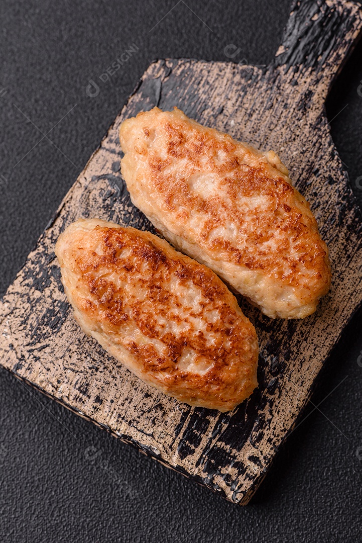 Deliciosas costeletas de peixe picado frito fresco com especiarias e ervas sobre um fundo escuro de concreto