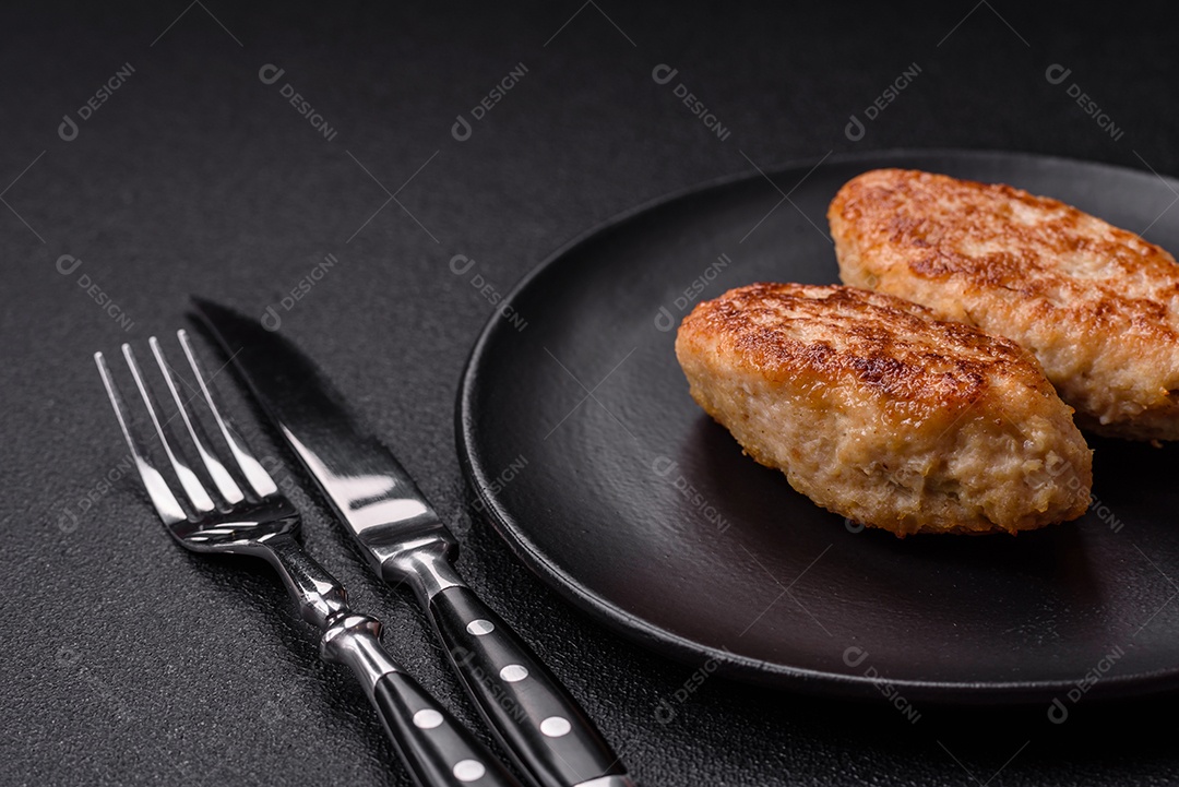 Deliciosas costeletas de peixe picado frito fresco com especiarias e ervas sobre um fundo escuro de concreto