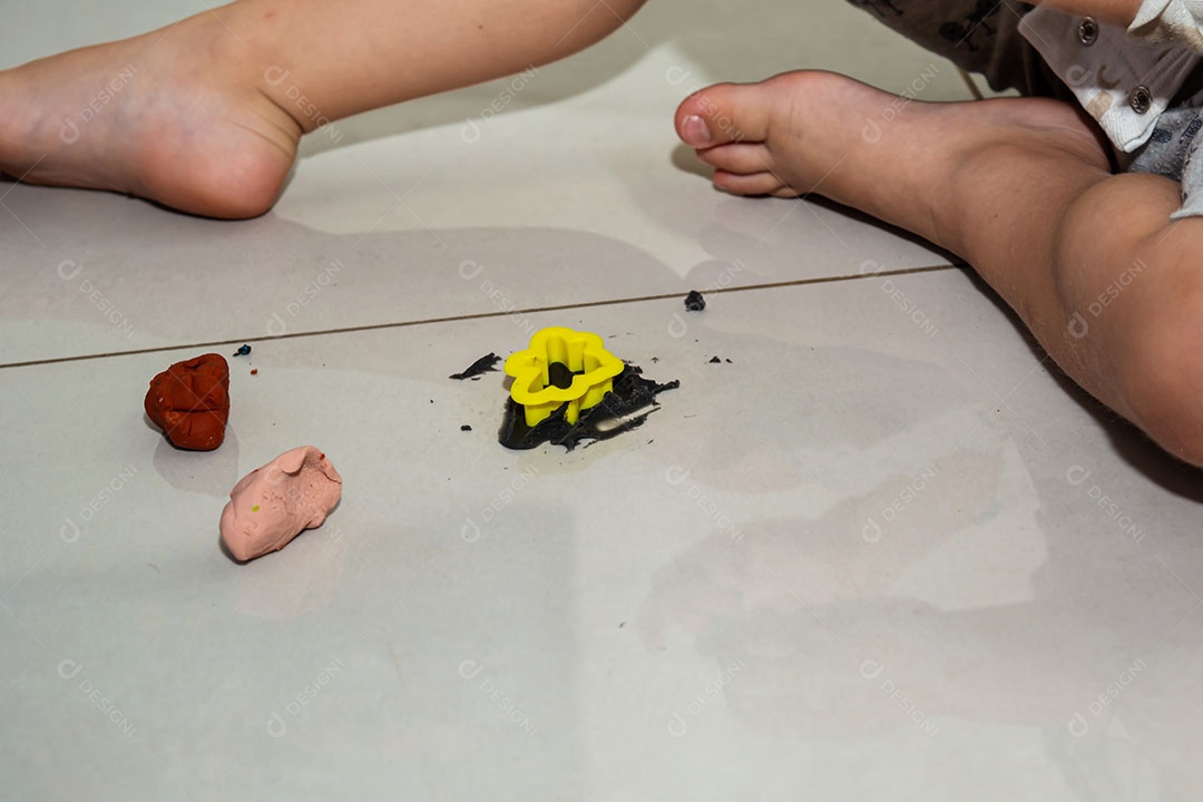 Criança brincando com massinha no chão em casa