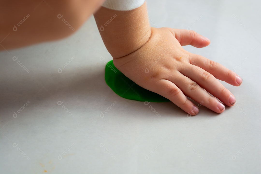 Criança brincando com massinha no chão em casa