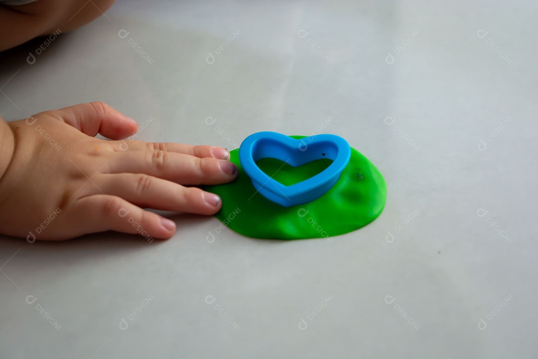 Criança brincando com massinha no chão em casa