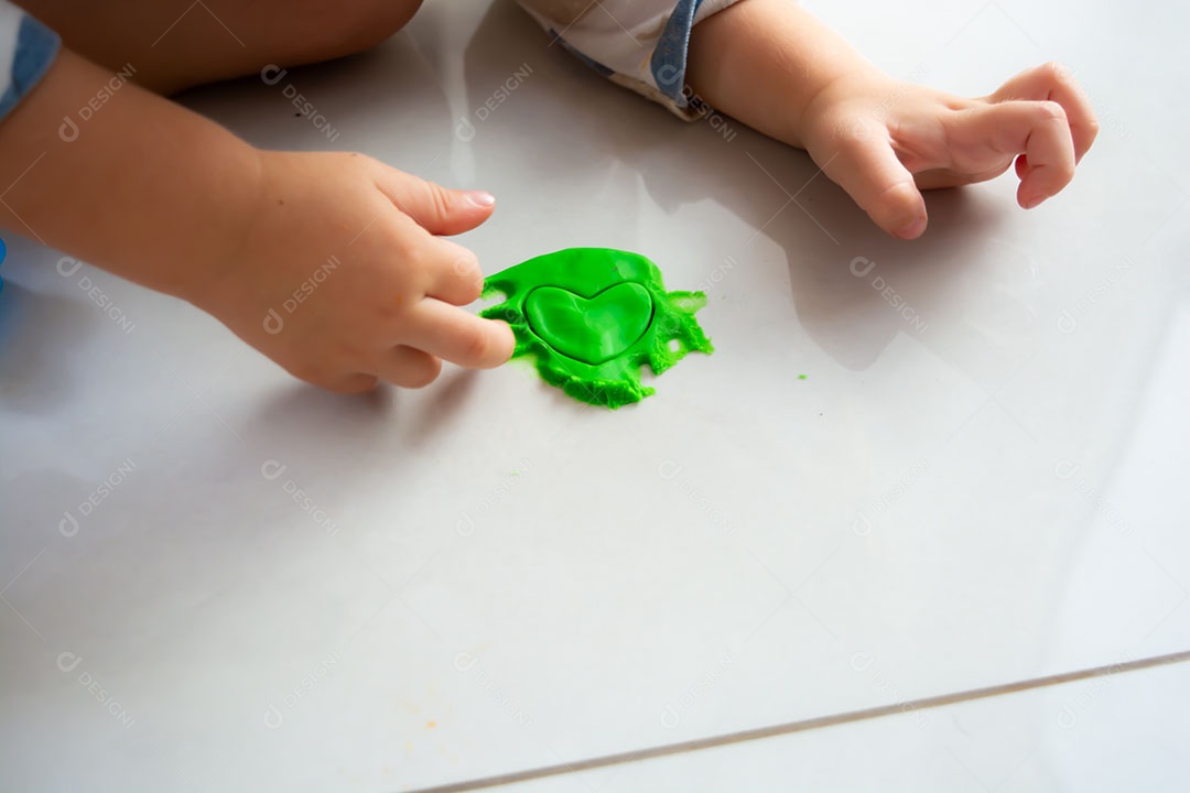 Criança brincando com massinha no chão em casa