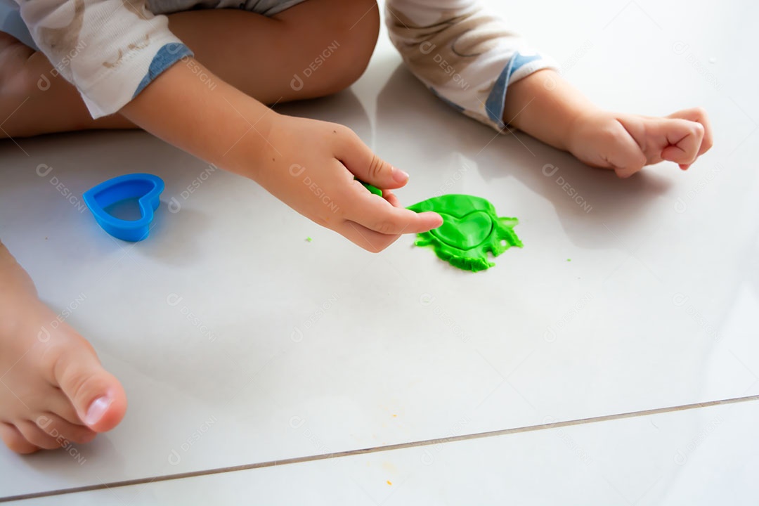 Criança brincando com massinha no chão em casa