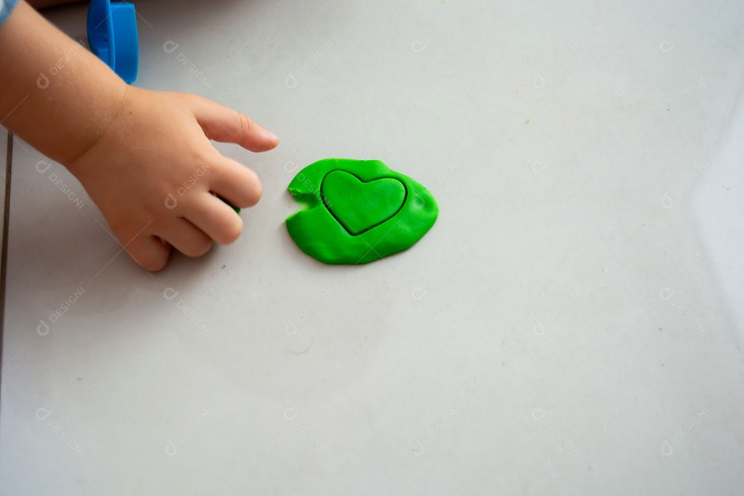 Criança brincando com massinha no chão em casa