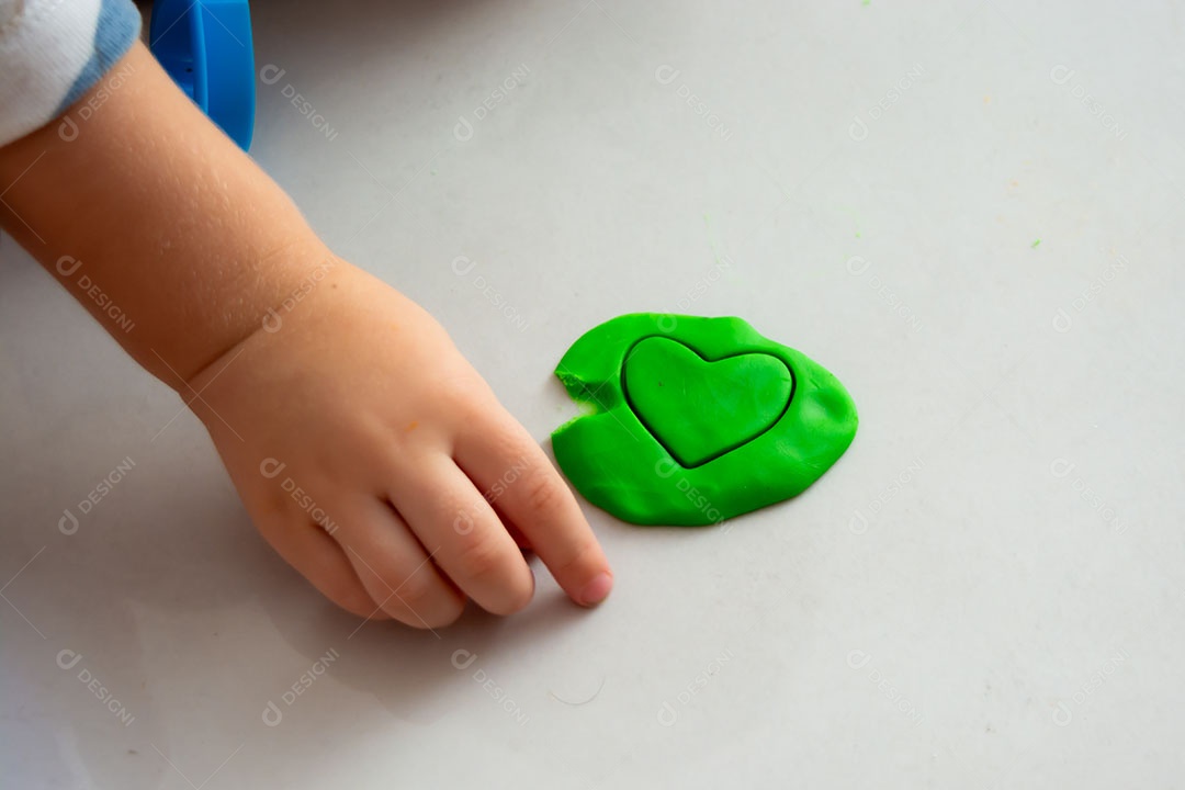 Criança brincando com massinha no chão em casa