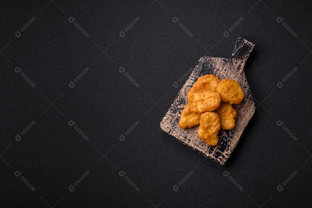 Deliciosos nuggets de frango crocantes frescos em um fundo escuro de concreto. Alimentos não saudáveis, fast food