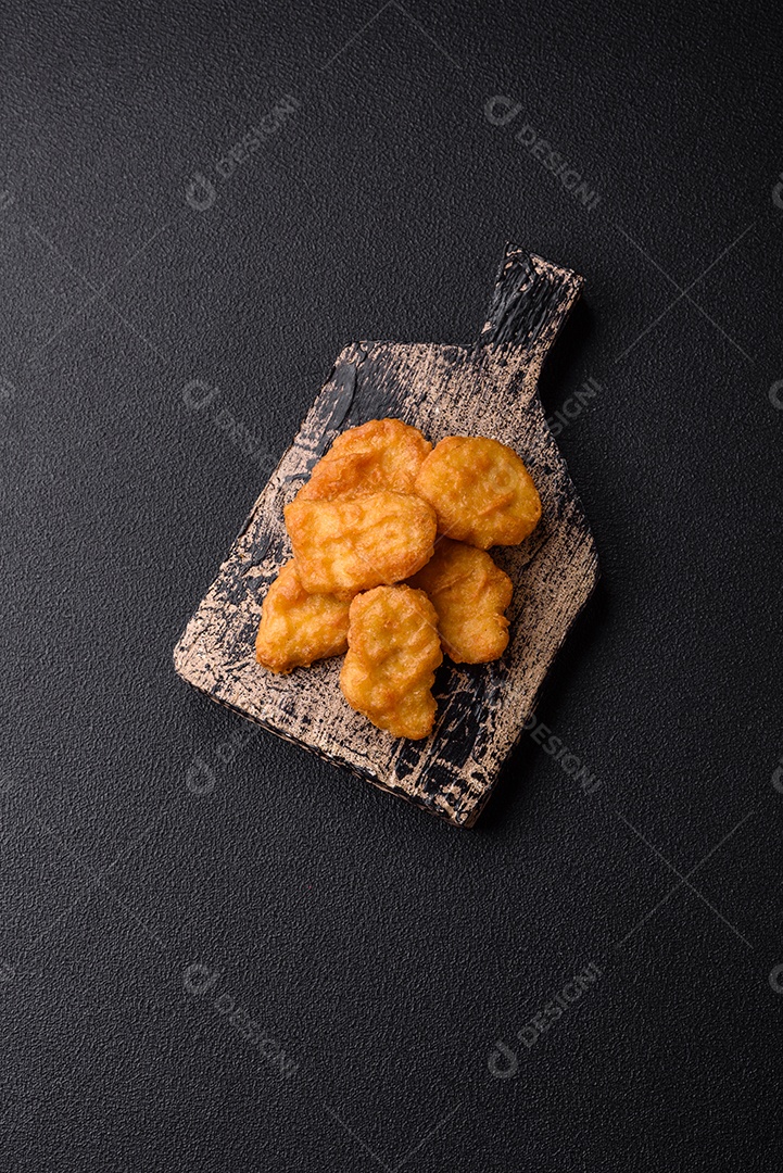 Deliciosos nuggets de frango crocantes frescos em um fundo escuro de concreto. Alimentos não saudáveis, fast food