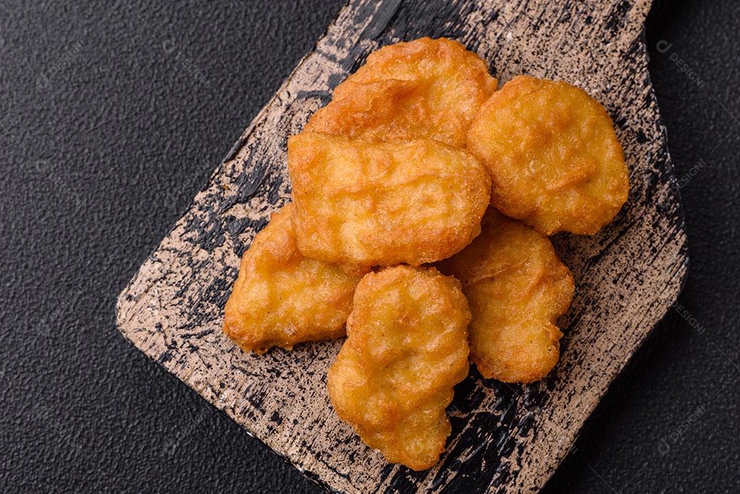 Deliciosos nuggets de frango crocantes frescos em um fundo escuro de concreto. Alimentos não saudáveis, fast food