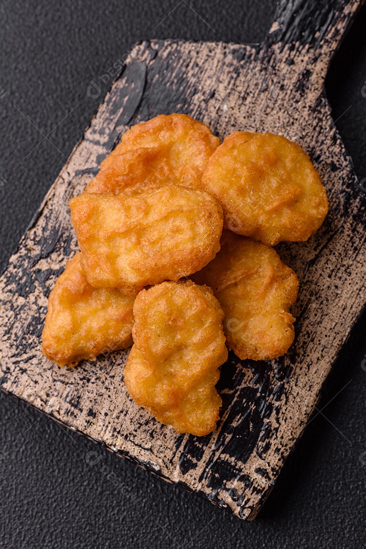 Deliciosos nuggets de frango crocantes frescos em um fundo escuro de concreto. Alimentos não saudáveis, fast food
