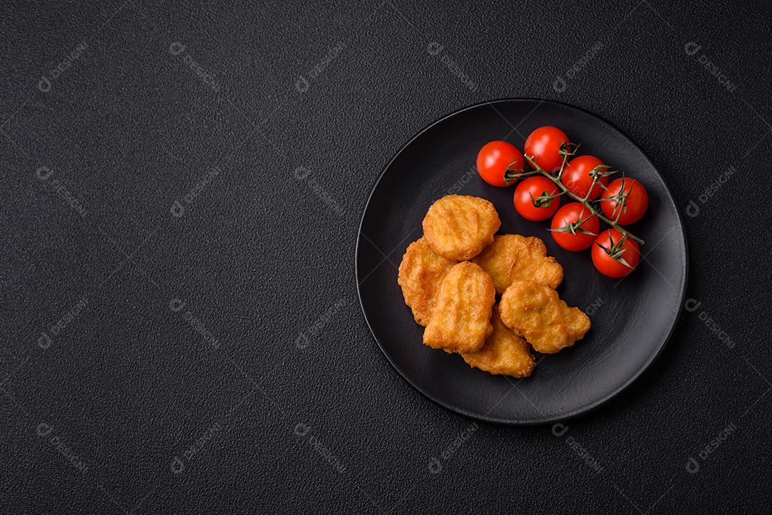 Deliciosos nuggets de frango crocantes frescos em um fundo escuro de concreto. Alimentos não saudáveis, fast food