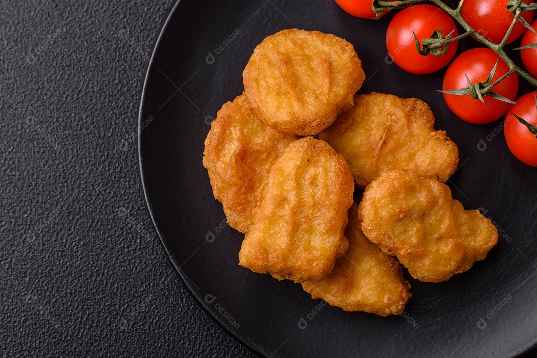 Deliciosos nuggets de frango crocantes frescos em um fundo escuro de concreto. Alimentos não saudáveis, fast food