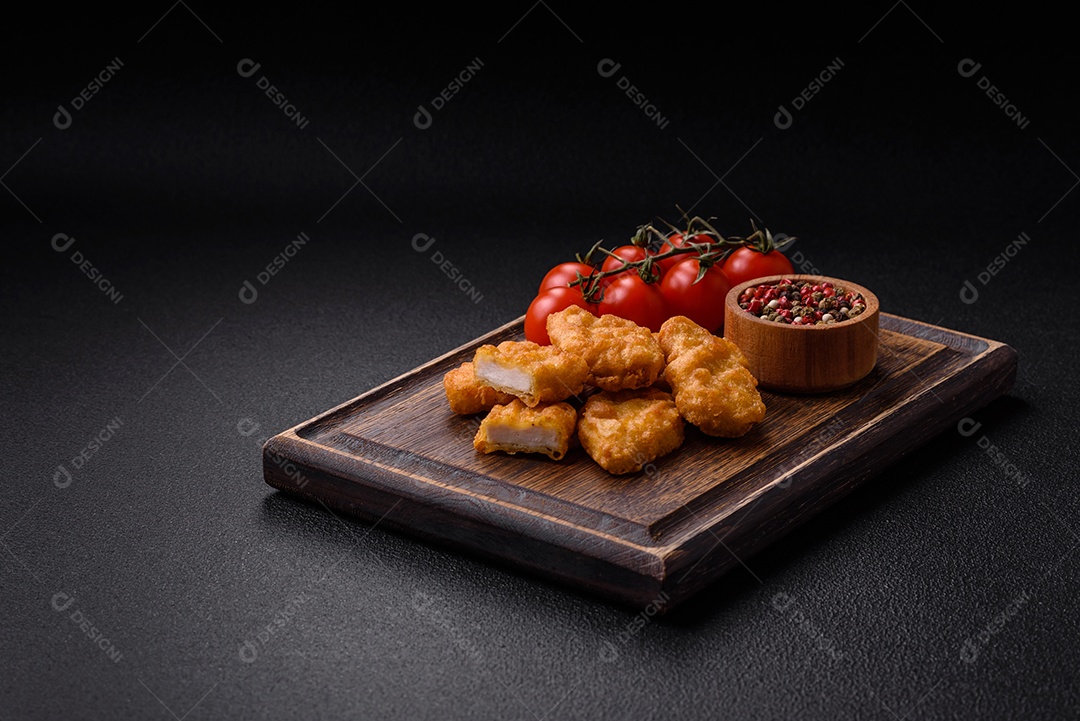 Deliciosos nuggets de frango crocantes frescos em um fundo escuro de concreto. Alimentos não saudáveis, fast food