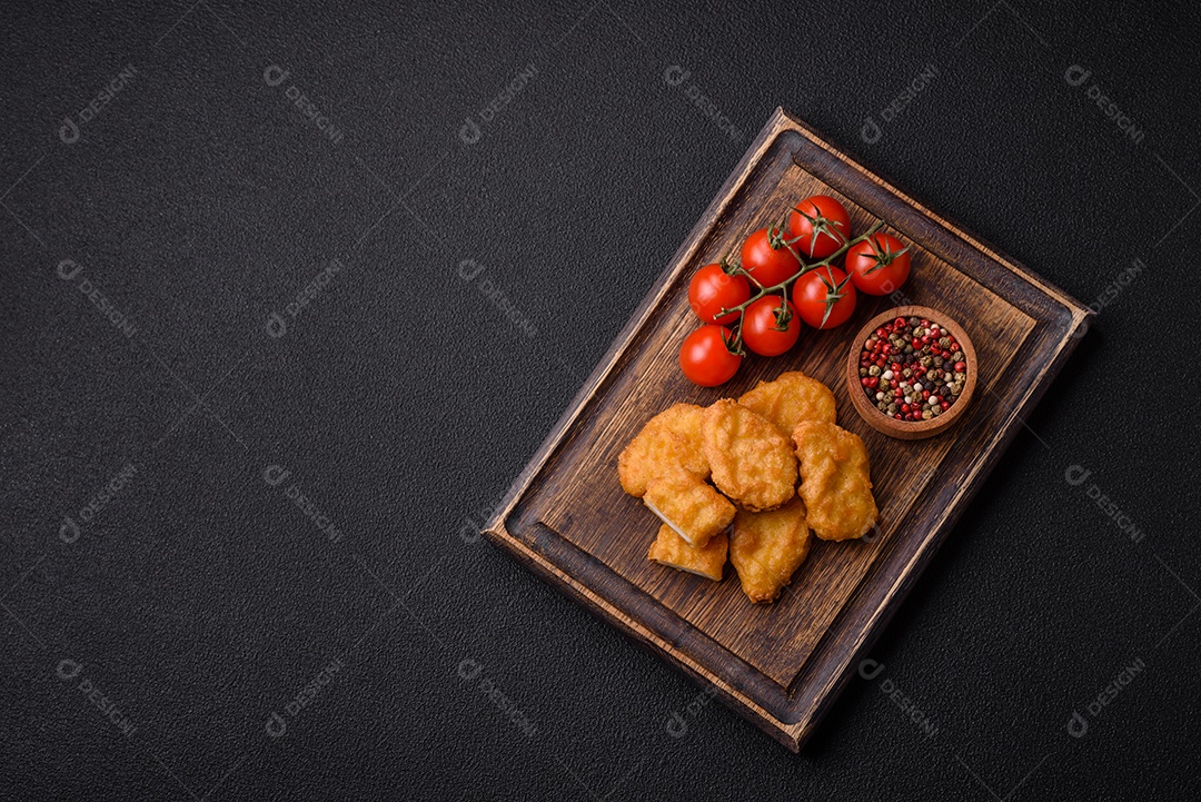 Deliciosos nuggets de frango crocantes frescos em um fundo escuro de concreto. Alimentos não saudáveis, fast food
