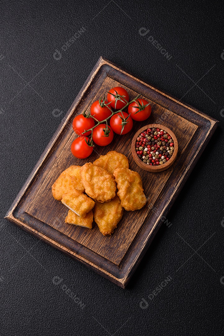 Deliciosos nuggets de frango crocantes frescos em um fundo escuro de concreto. Alimentos não saudáveis, fast food