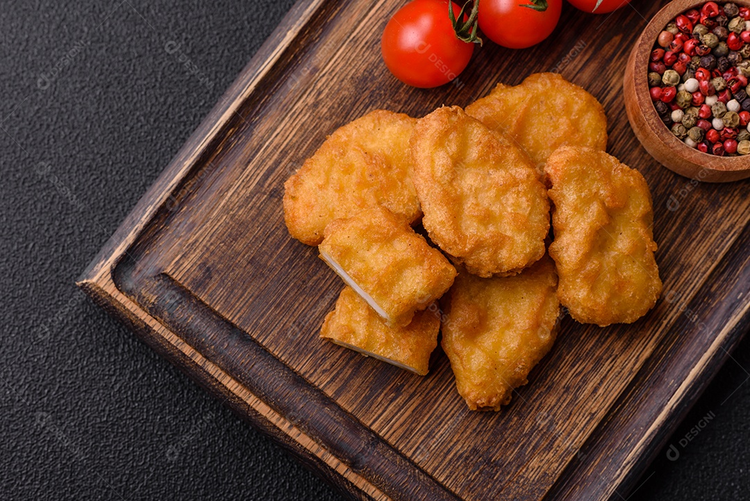 Deliciosos nuggets de frango crocantes frescos em um fundo escuro de concreto. Alimentos não saudáveis, fast food