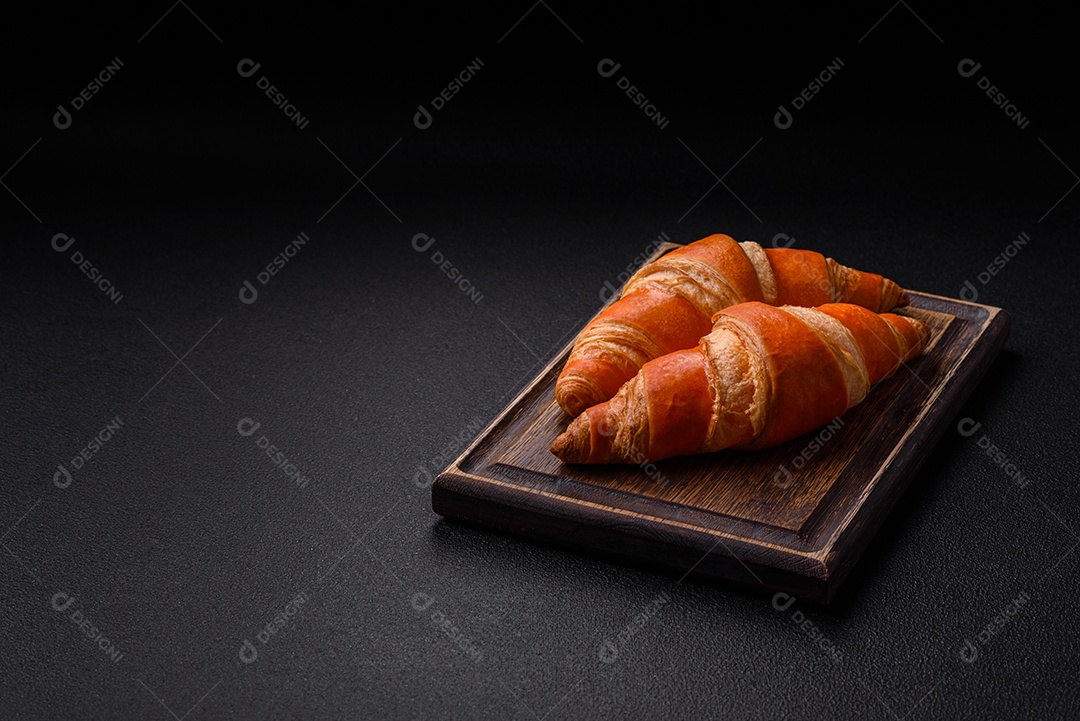 Deliciosos croissants franceses frescos e crocantes com recheio doce sobre fundo escuro de concreto
