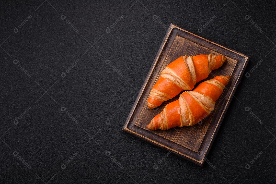 Deliciosos croissants franceses frescos e crocantes com recheio doce sobre fundo escuro de concreto