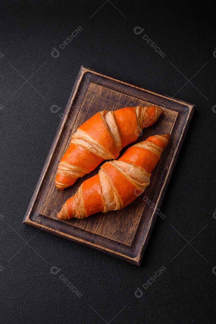 Deliciosos croissants franceses frescos e crocantes com recheio doce sobre fundo escuro de concreto