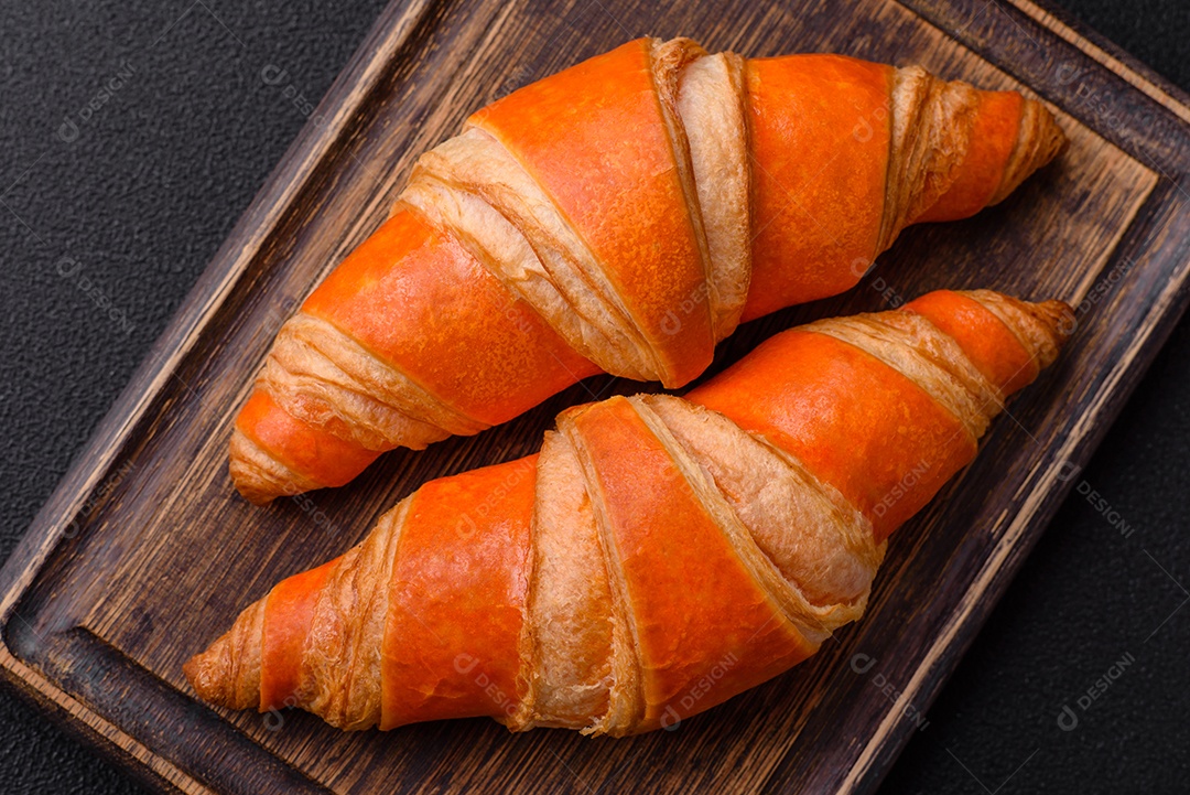 Deliciosos croissants franceses frescos e crocantes com recheio doce sobre fundo escuro de concreto
