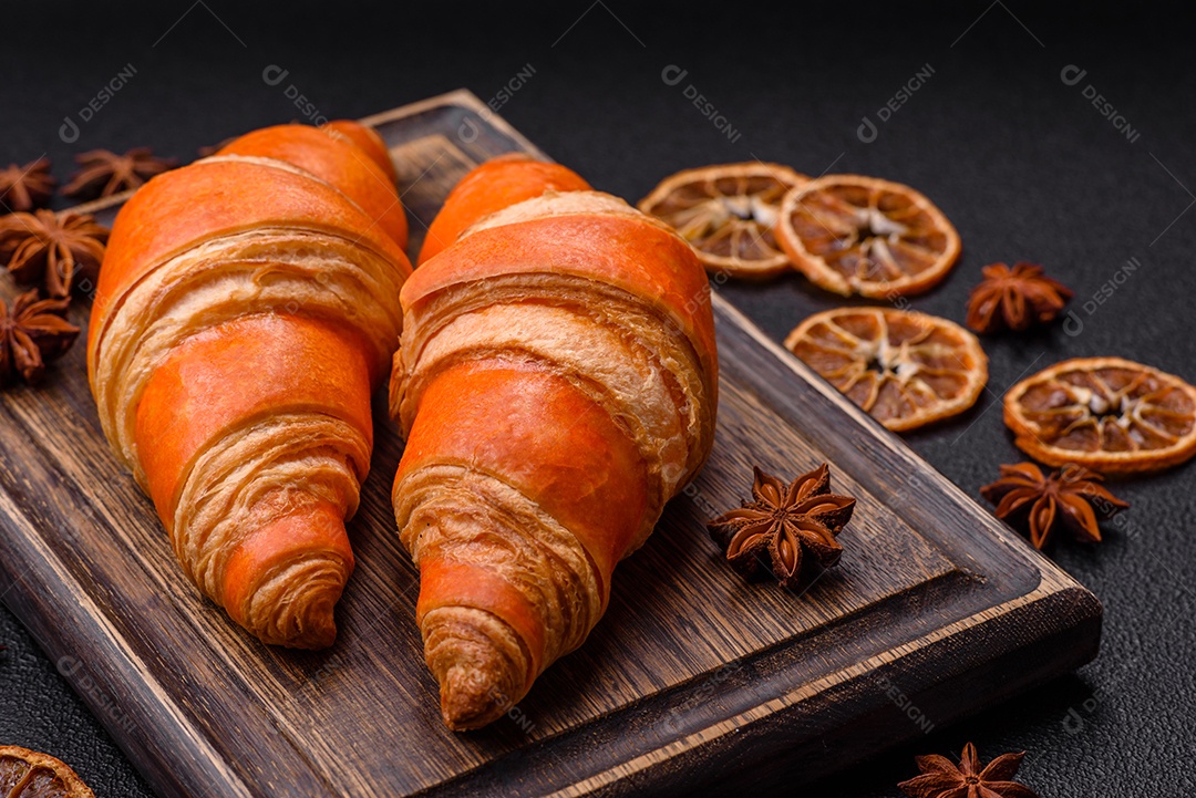 Deliciosos croissants franceses frescos e crocantes com recheio doce sobre fundo escuro de concreto