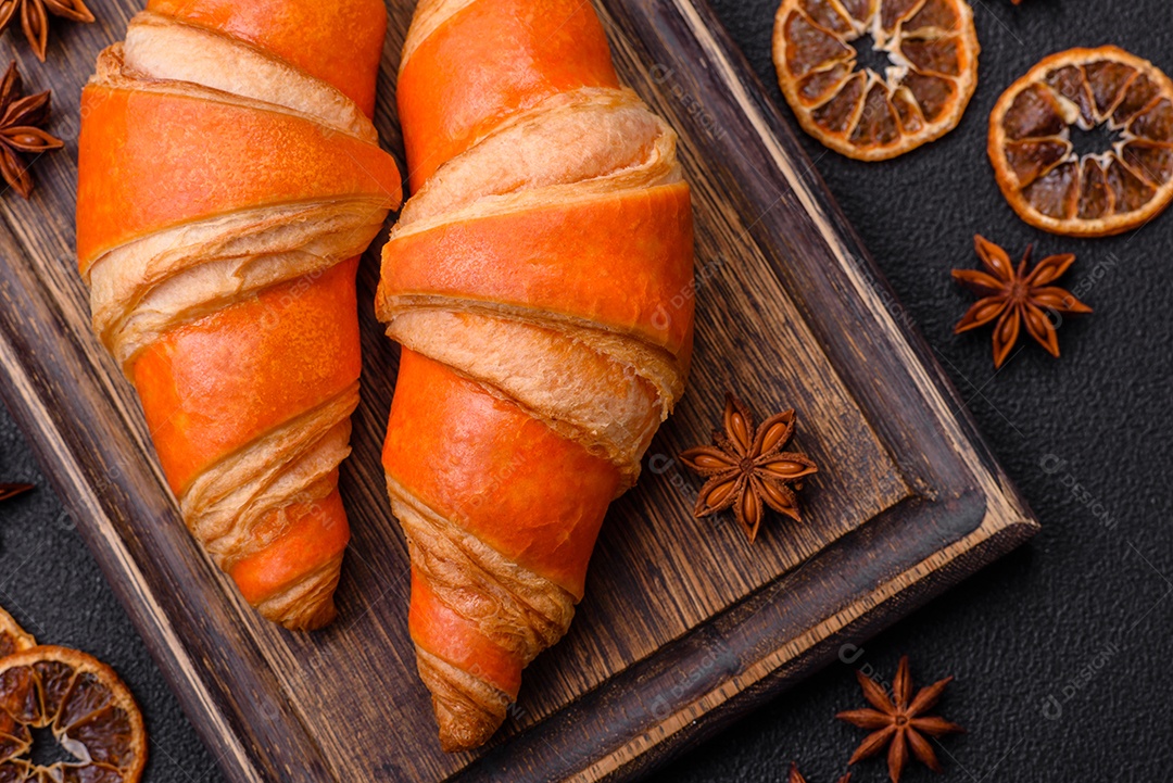 Deliciosos croissants franceses frescos e crocantes com recheio doce sobre fundo escuro de concreto