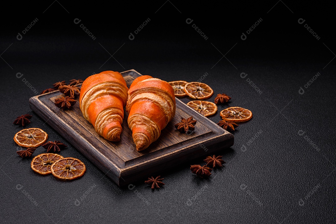 Deliciosos croissants franceses frescos e crocantes com recheio doce sobre fundo escuro de concreto