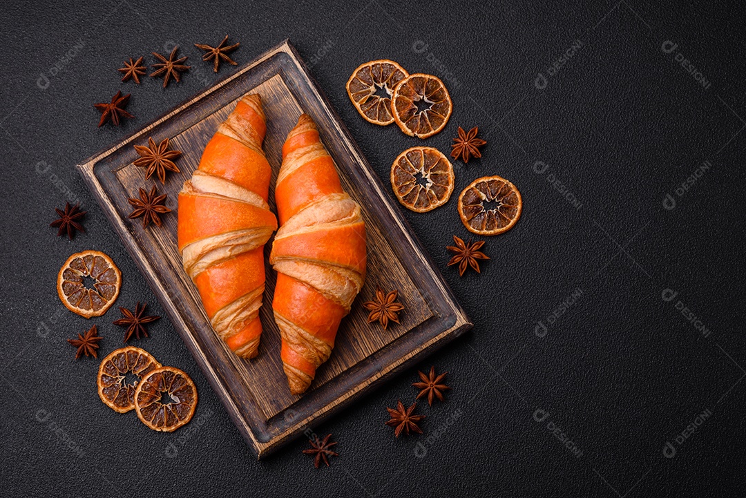 Deliciosos croissants franceses frescos e crocantes com recheio doce sobre fundo escuro de concreto