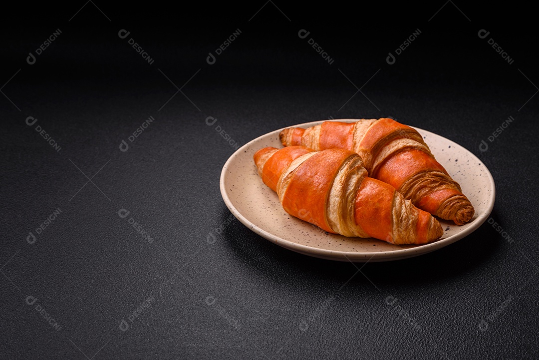 Deliciosos croissants franceses frescos e crocantes com recheio doce sobre fundo escuro de concreto