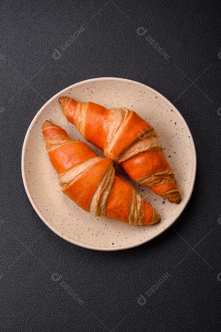 Deliciosos croissants franceses frescos e crocantes com recheio doce sobre fundo escuro de concreto