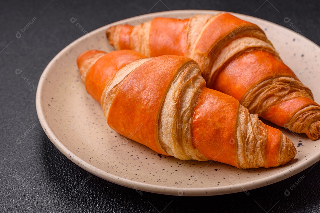 Deliciosos croissants franceses frescos e crocantes com recheio doce sobre fundo escuro de concreto