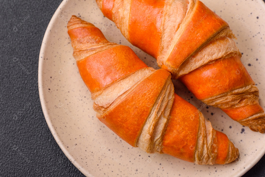 Deliciosos croissants franceses frescos e crocantes com recheio doce sobre fundo escuro de concreto