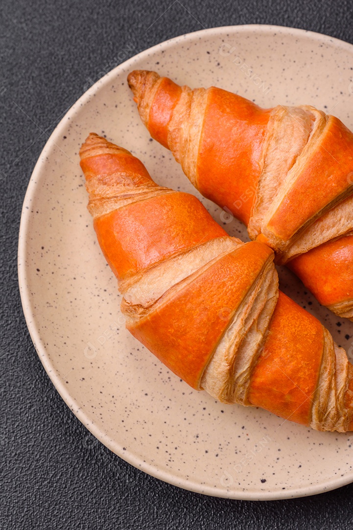 Deliciosos croissants franceses frescos e crocantes com recheio doce sobre fundo escuro de concreto