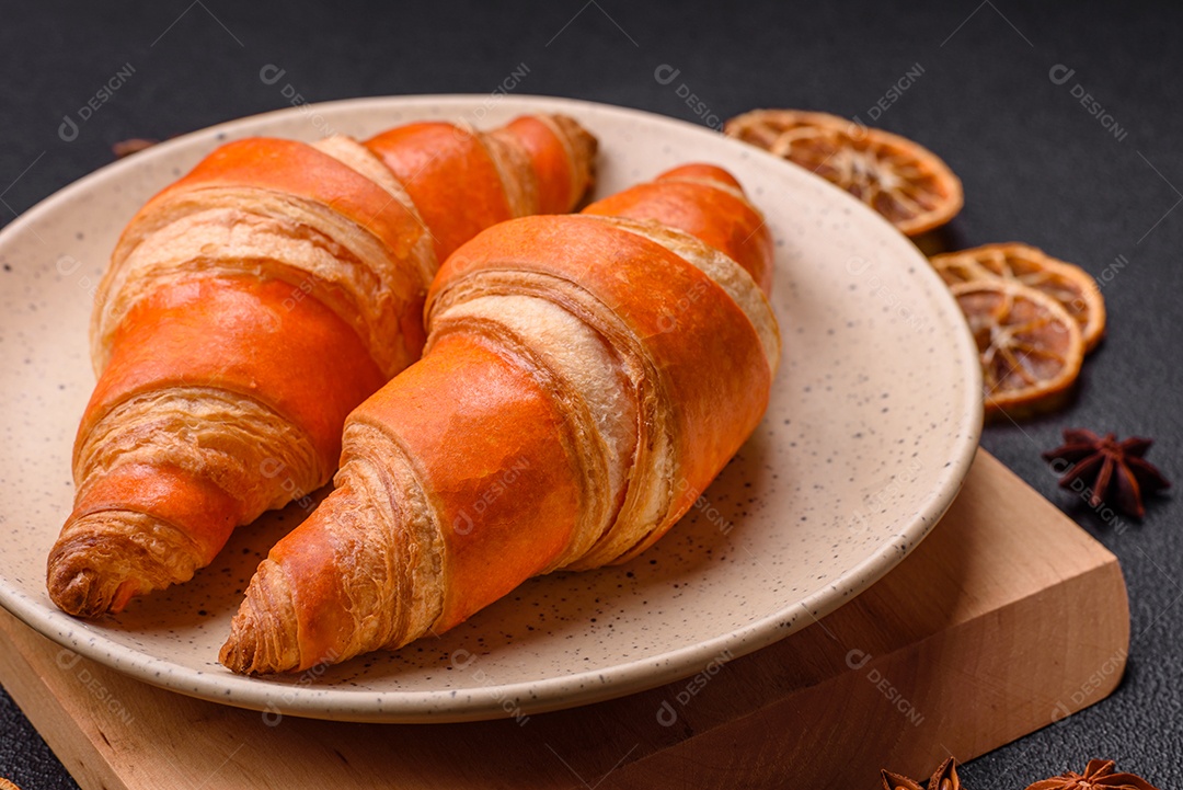 Deliciosos croissants franceses frescos e crocantes com recheio doce sobre fundo escuro de concreto