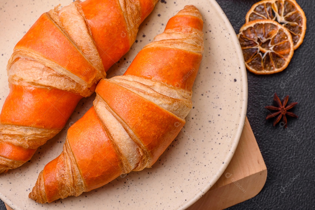 Deliciosos croissants franceses frescos e crocantes com recheio doce sobre fundo escuro de concreto